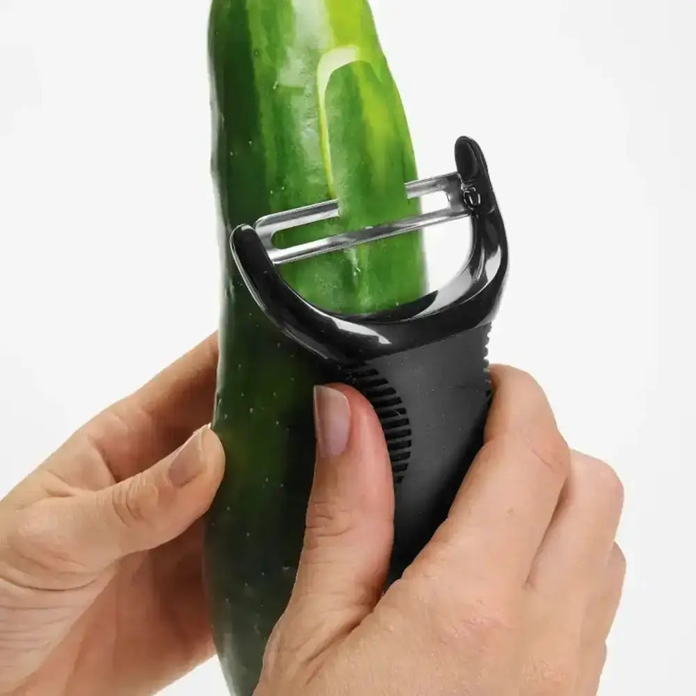 Person using a vegetable peeler to cut a cucumber on a white background