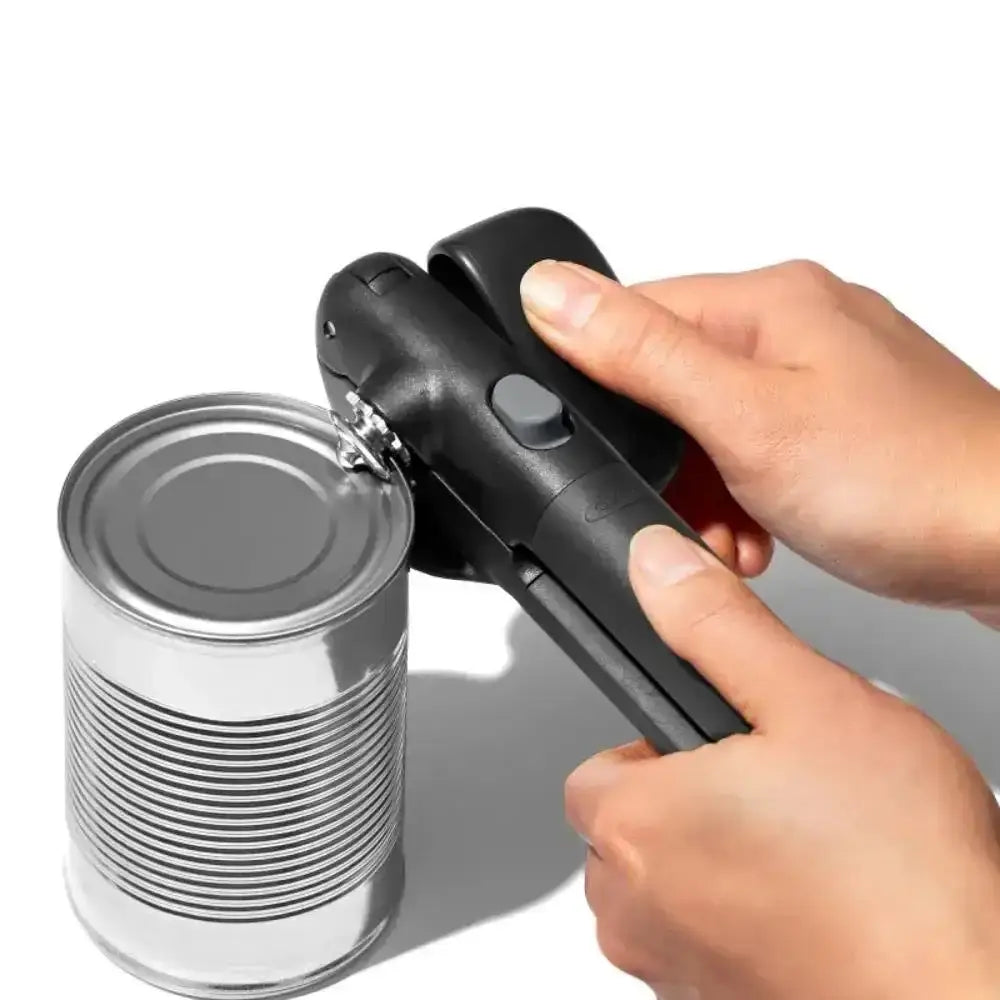 Hand using a can opener on a can against a white background