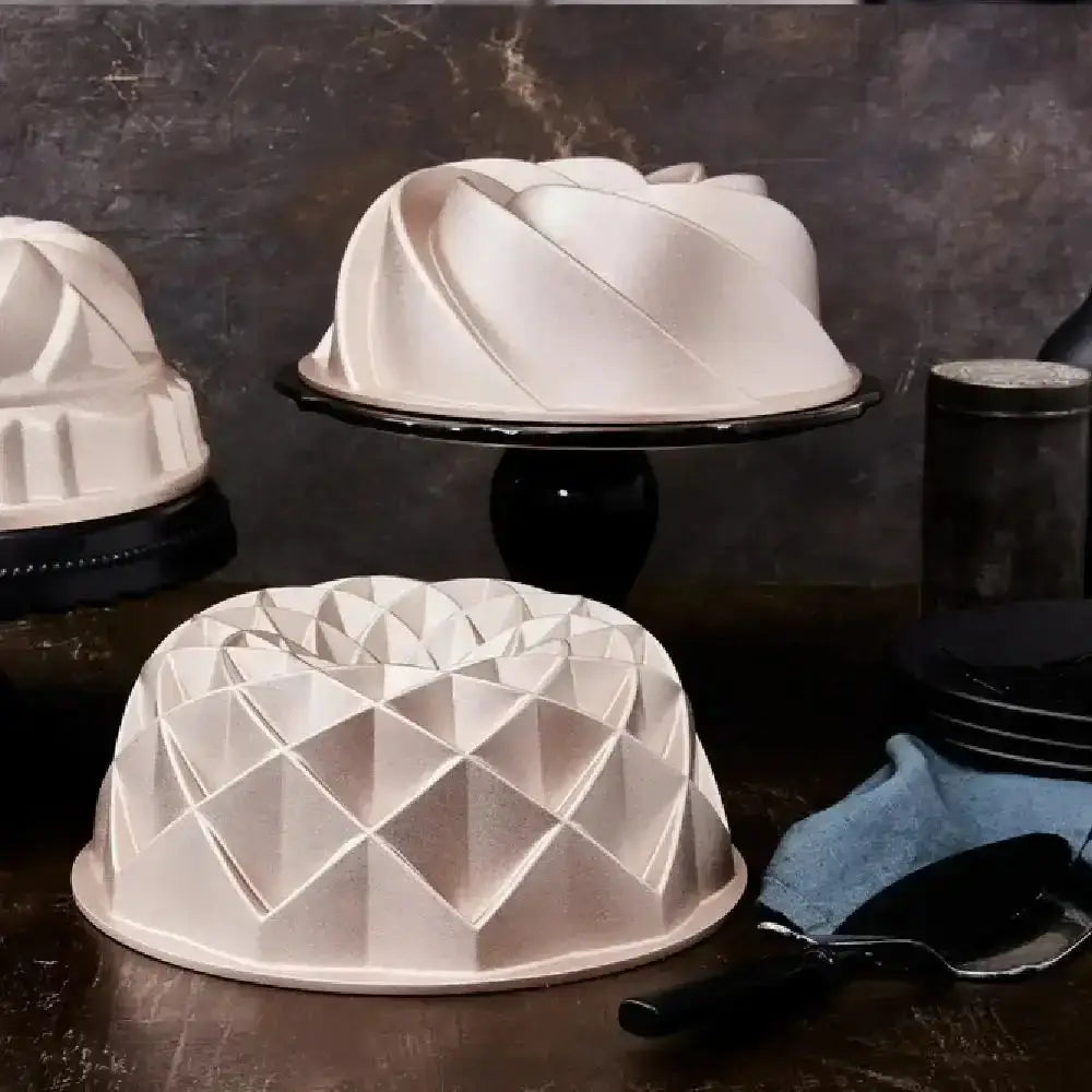 Two cake molds with geometric designs on a dark surface.