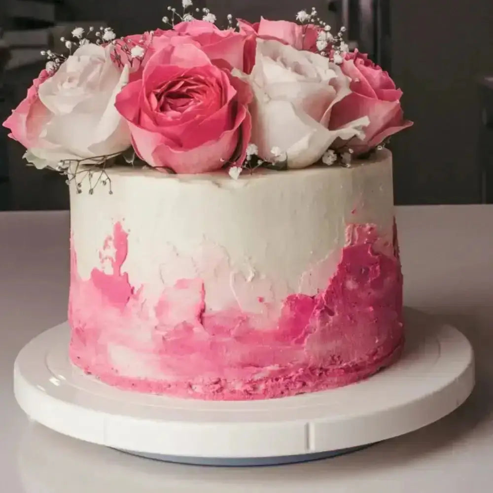 Pink and white cake with floral decorations on a white surface
