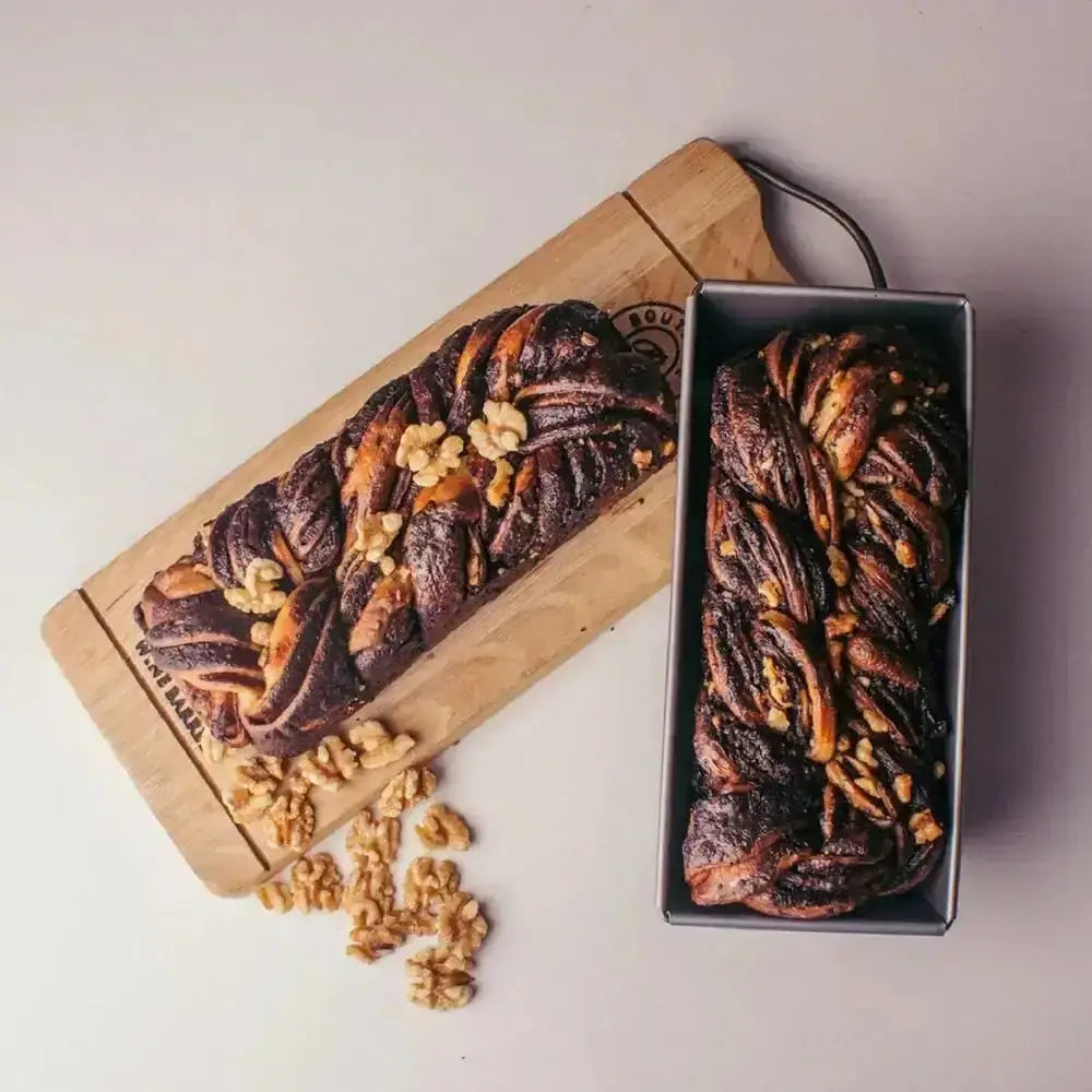 Braided bread with walnuts on a wooden board and in a black box.