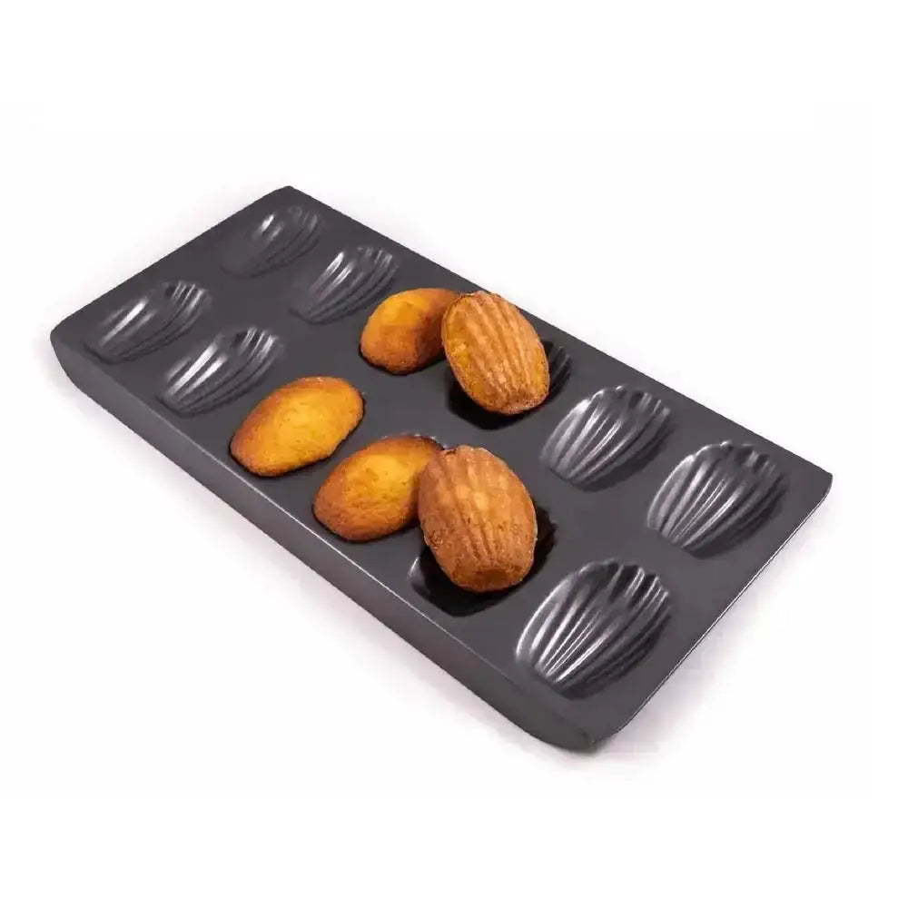 Baking tray with madeleine molds containing baked pastries on a white background
