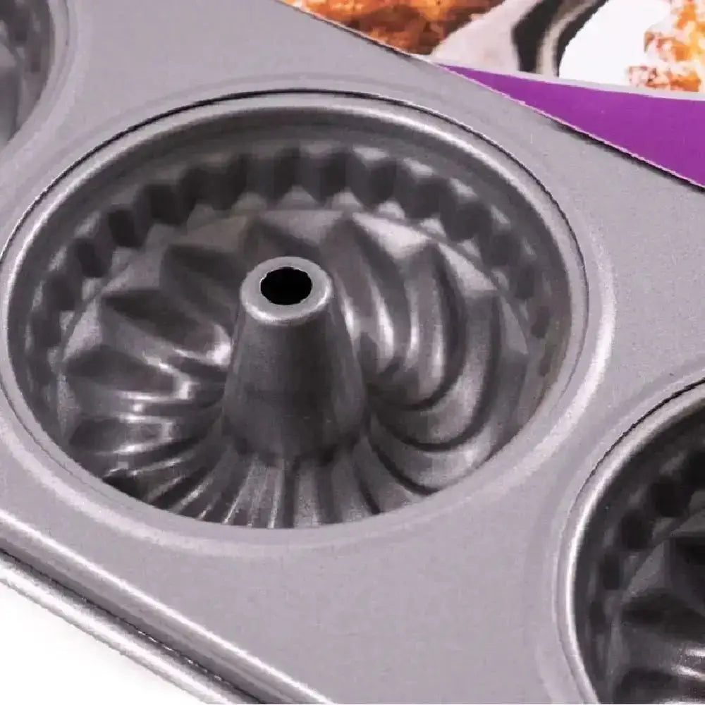 Metallic cake mold with intricate design on a blurred background