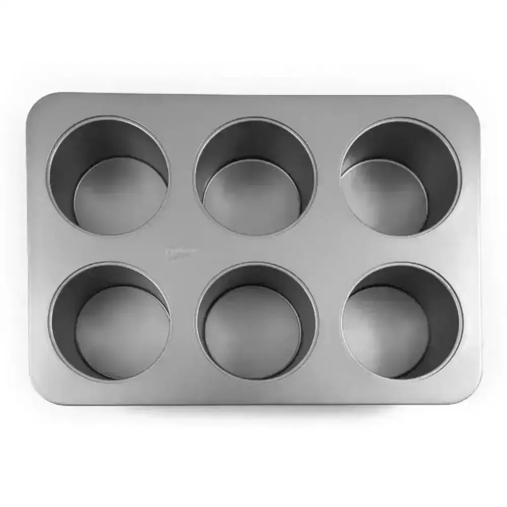 Silver non-stick six-cup muffin pan with rounded edges and uniform circular cavities for mini cheesecakes