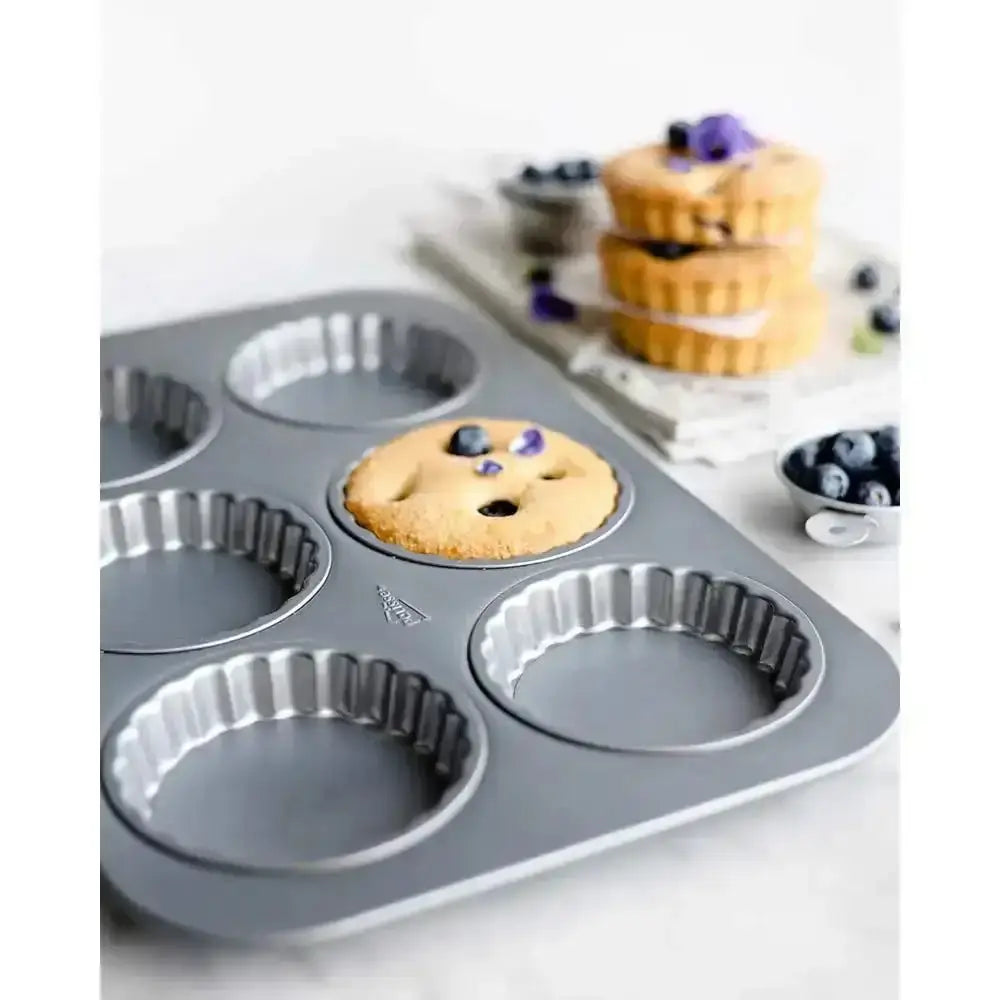 Muffin tin with a baked muffin on a white surface