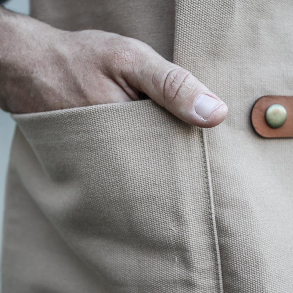 Close-up of a hand touching a beige fabric surface with a leather button.