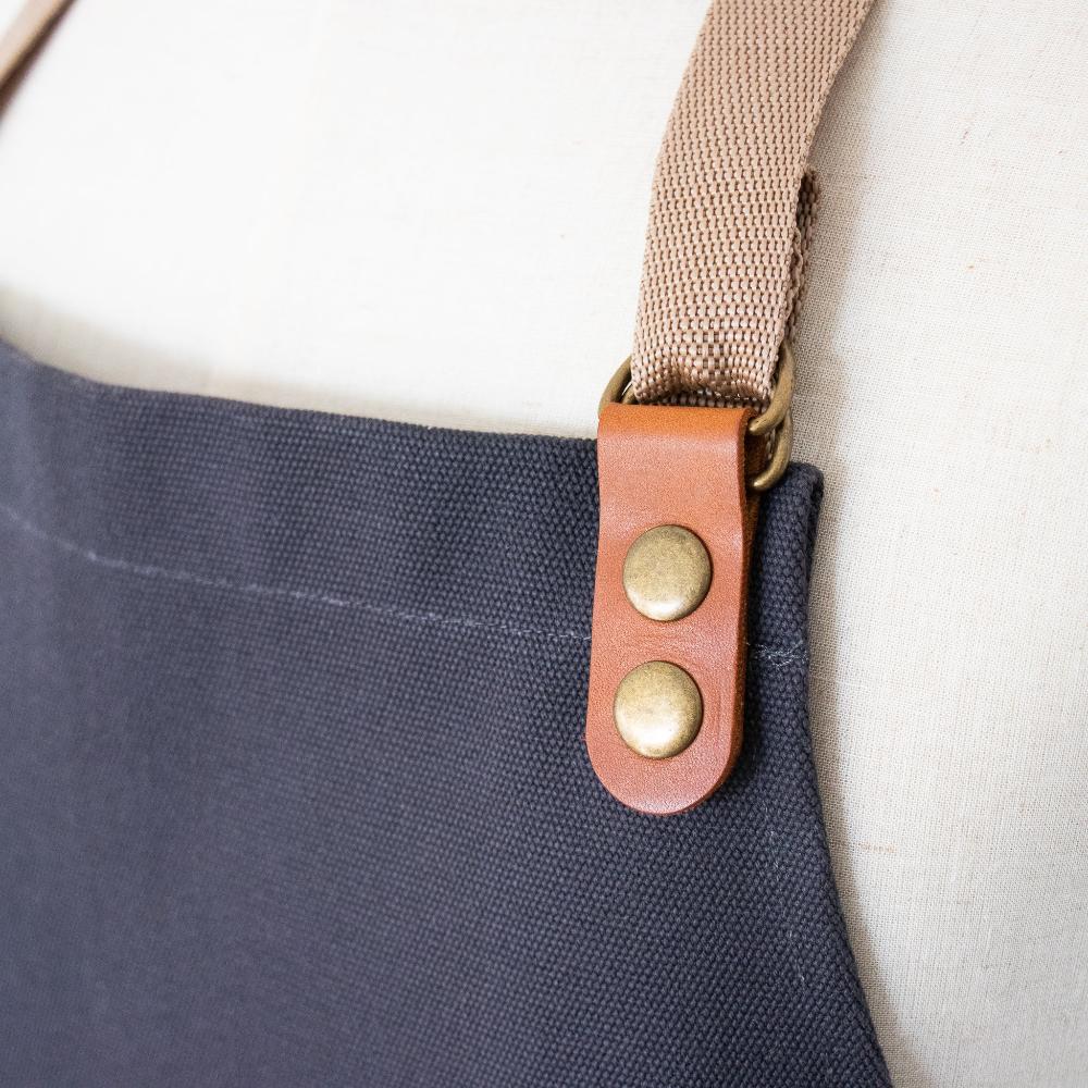 Navy blue bag with a brown strap and gold buttons on a white background