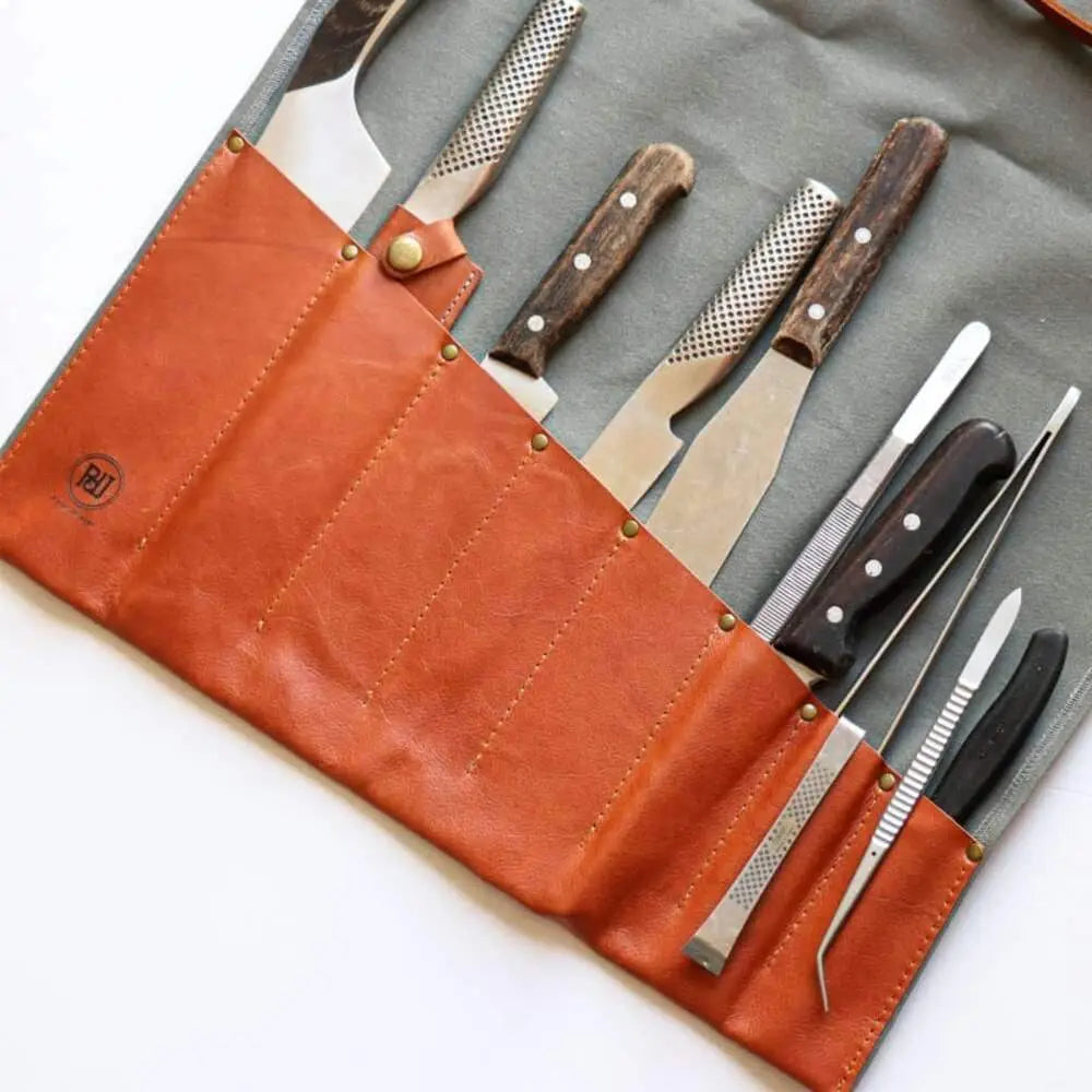 Tan leather kitchen knife roll with brass rivets containing knives and tools from Pieter De Jager canvas leather grey