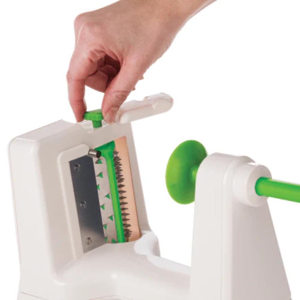 Hand using a white and green vegetable peeler on a white background