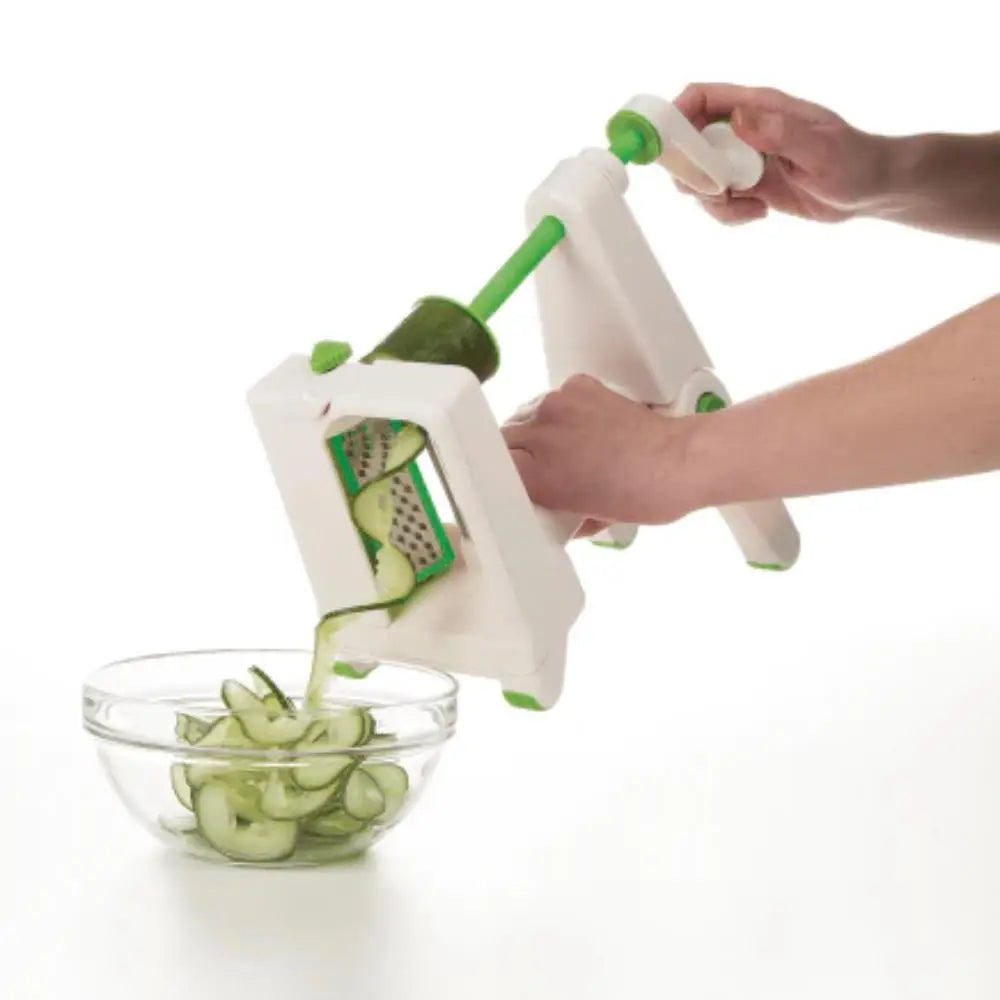 Person using a spiralizer to create zucchini noodles in a glass bowl on a white background
