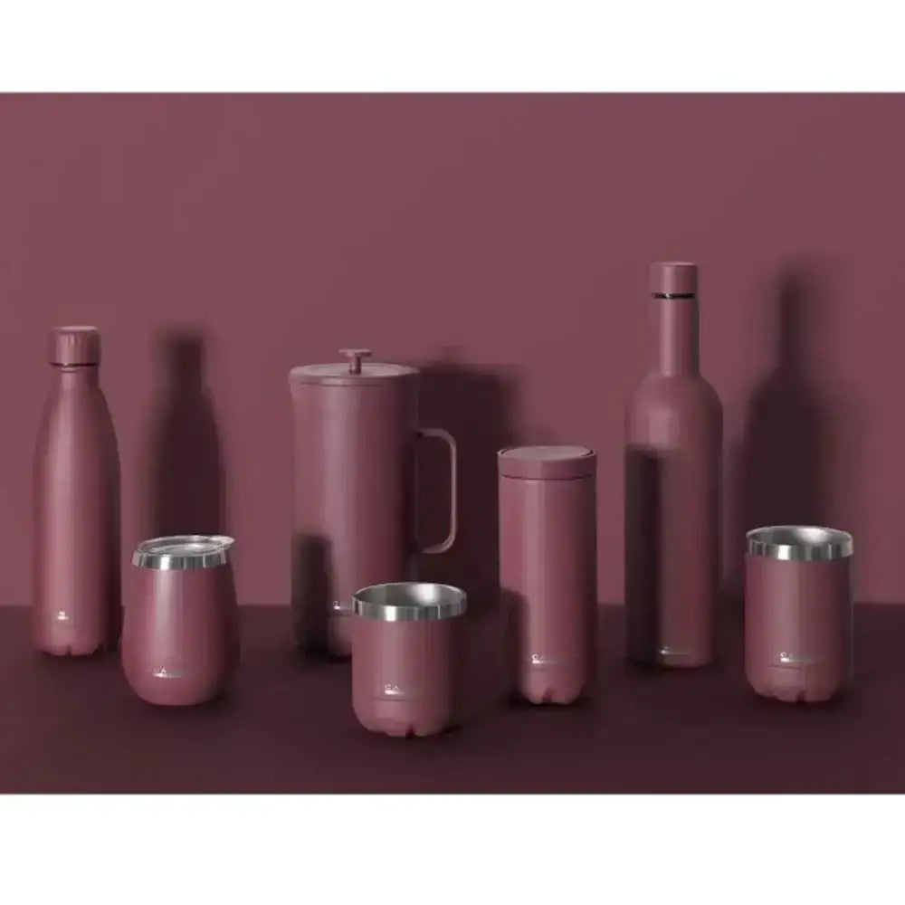 Set of pink stainless steel kitchenware items on a maroon background