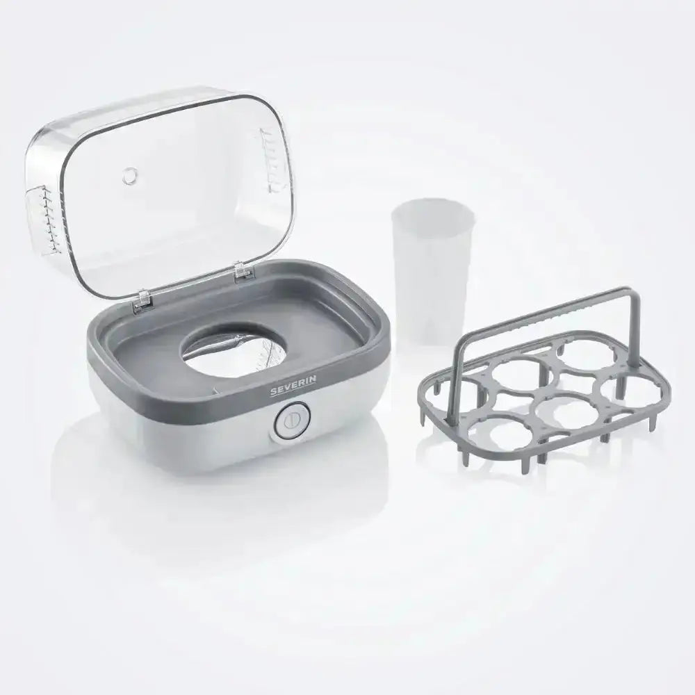 Electric egg boiler with open lid, egg holder for six eggs, and a measuring cup on white background.