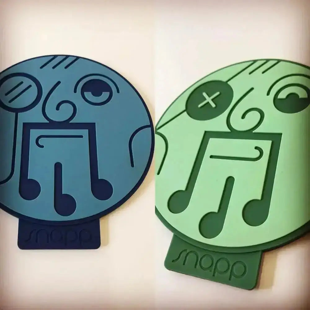 Two circular silicone-coated phone stand pads in blue and green with stylized musical notes and snapp branding