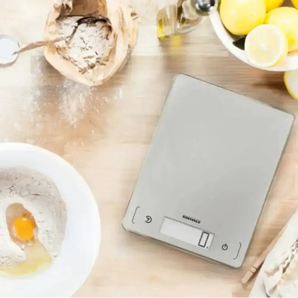 Digital kitchen scale on a wooden surface with ingredients around