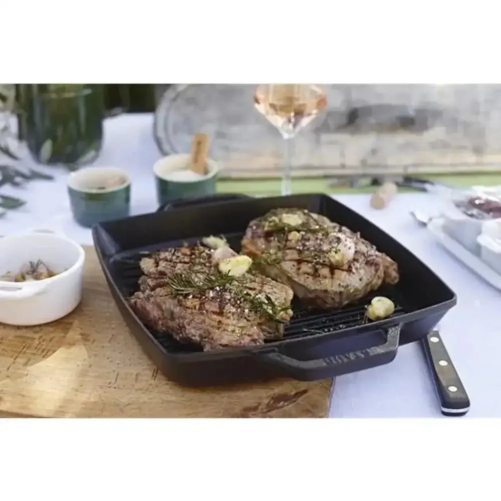 Staub square cast iron double handle grill pan 28cm black with two grilled steaks and herbs on top