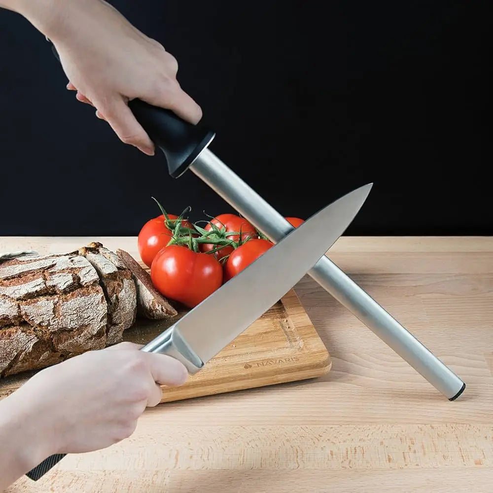 Knife sharpener being used on a chef's knife with bread and tomatoes in the background