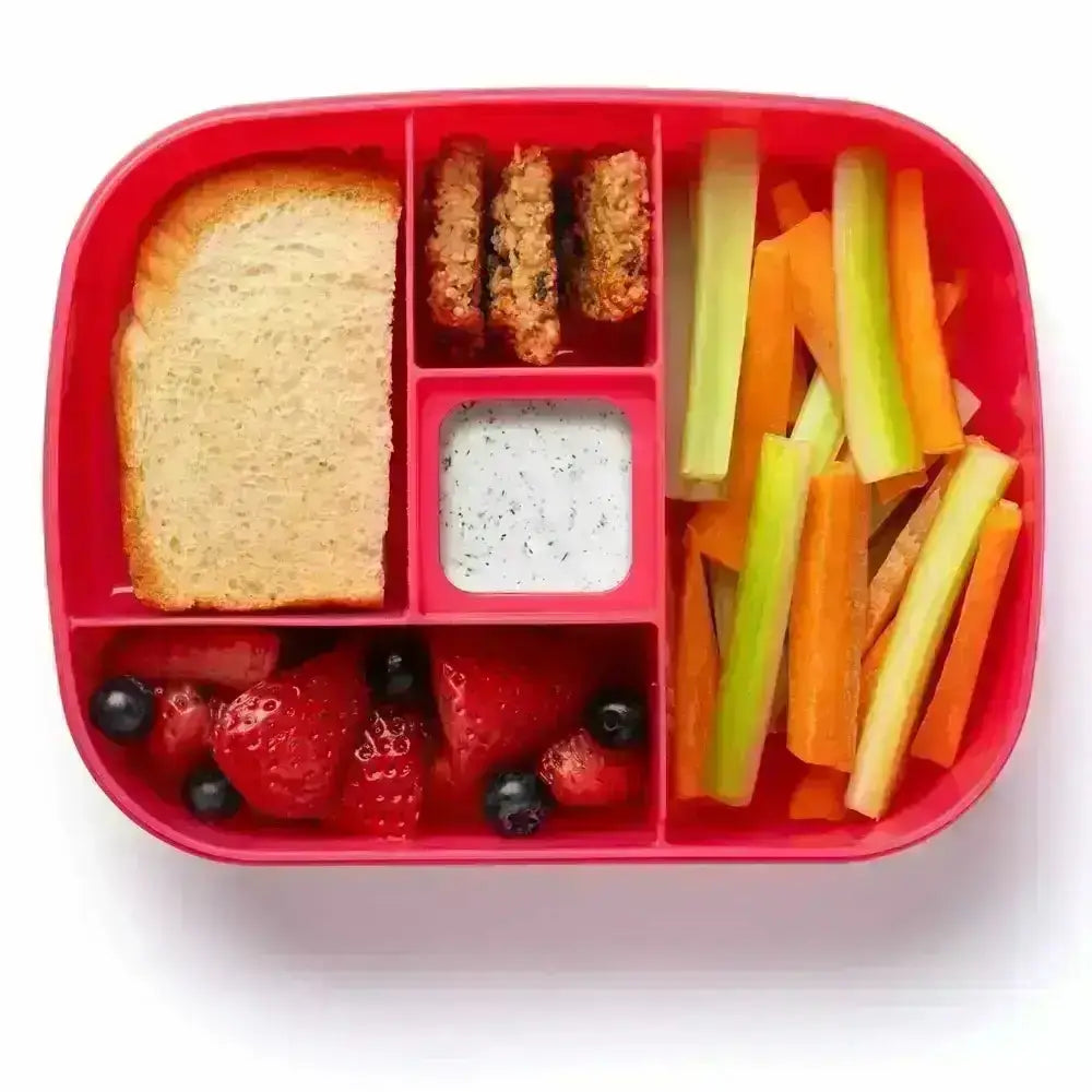 Red bento box with compartments containing a sandwich, crackers, dip, and vegetable sticks on a white background.