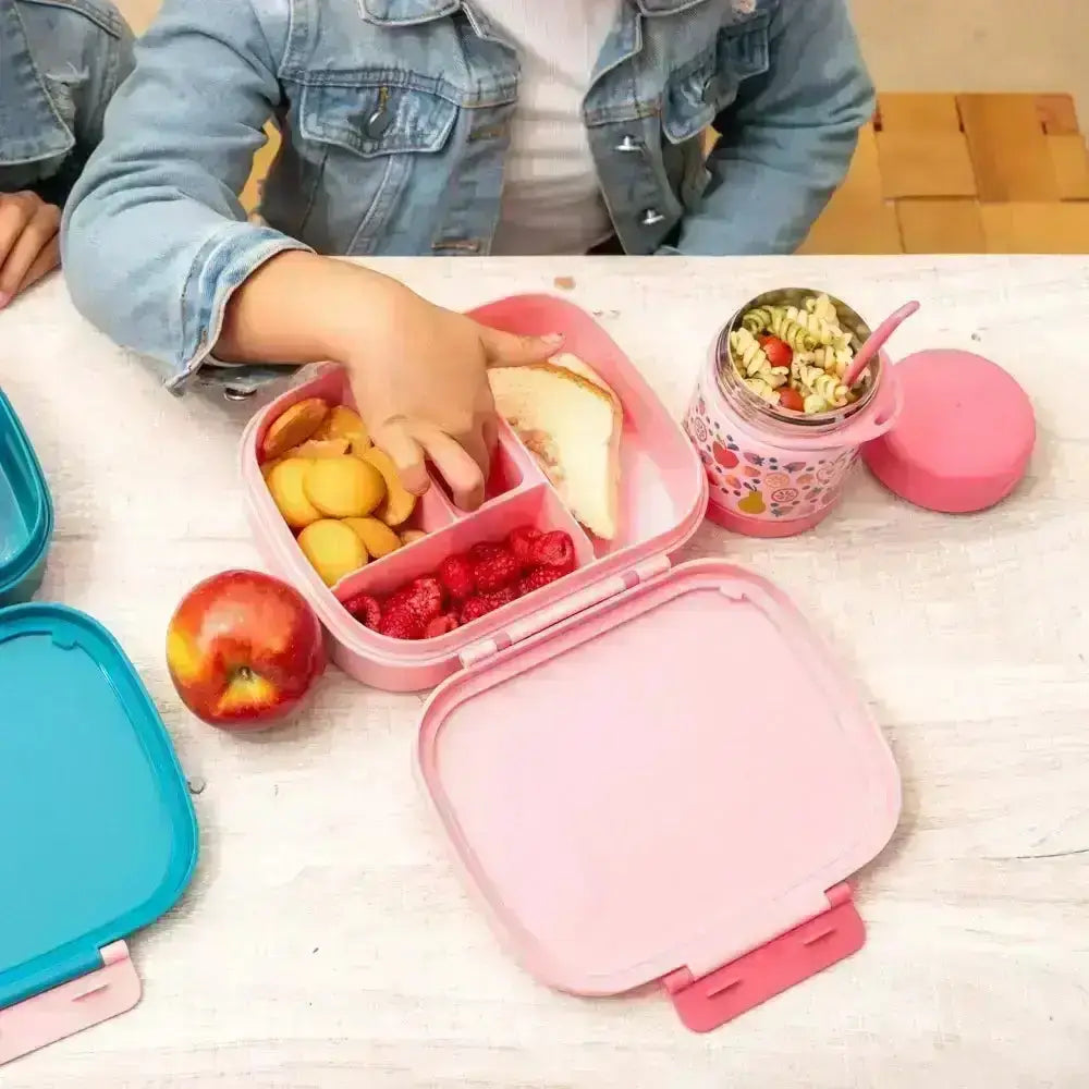 Child reaching into a pink bento box with food on a white surface