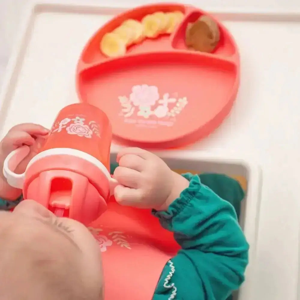 Red children's plate and cup set with food on a white tray