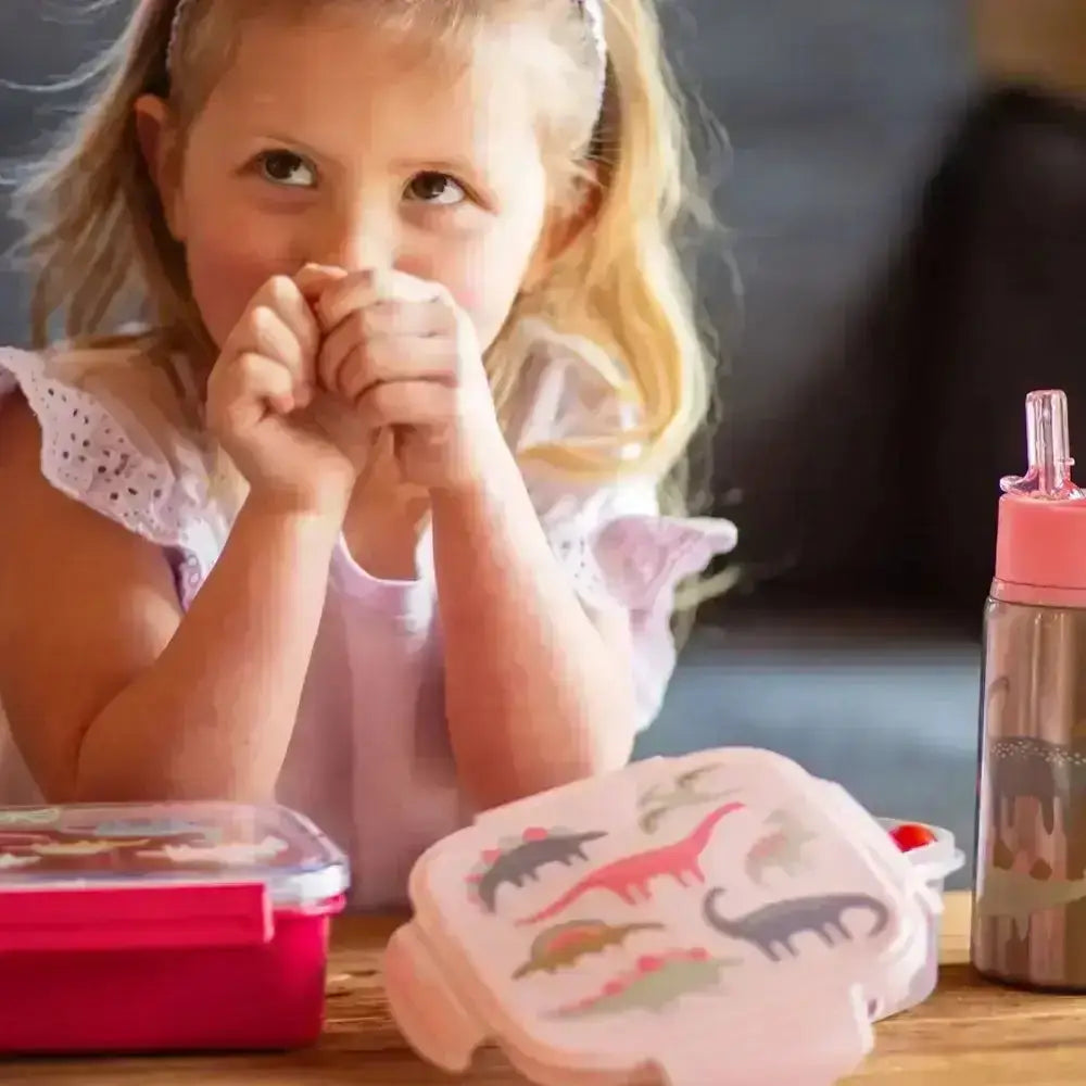 Child with dinosaur-themed lunch box and water bottle on a table