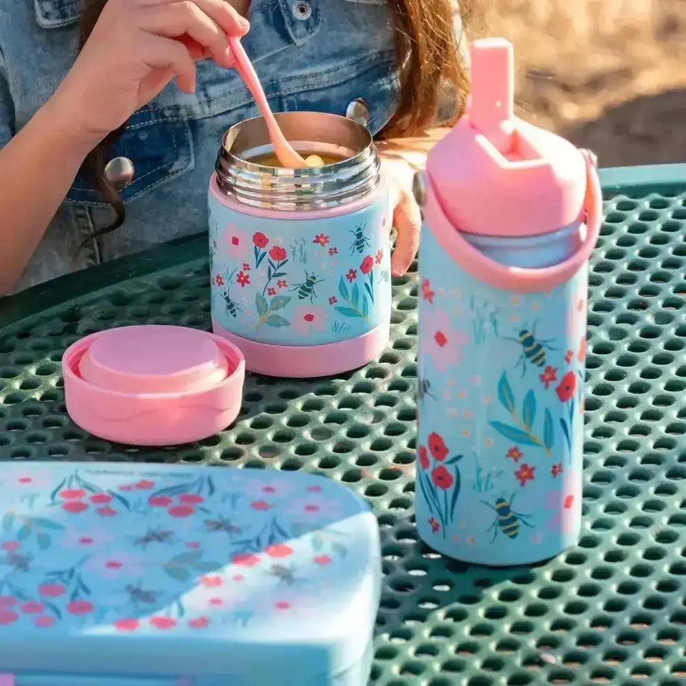 Children's floral-themed lunch set with thermos, container, and bottle on a green surface.