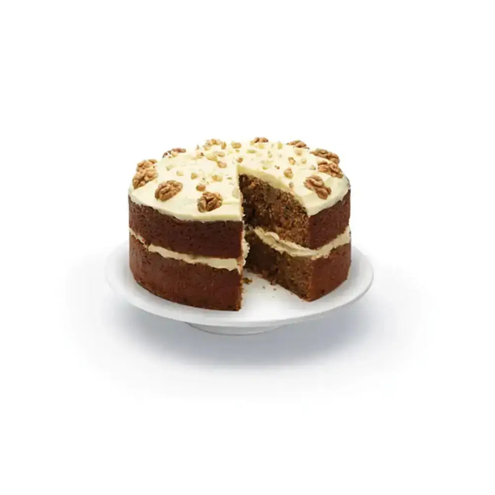 Two-layered cake with white frosting and nuts on a white plate against a white background