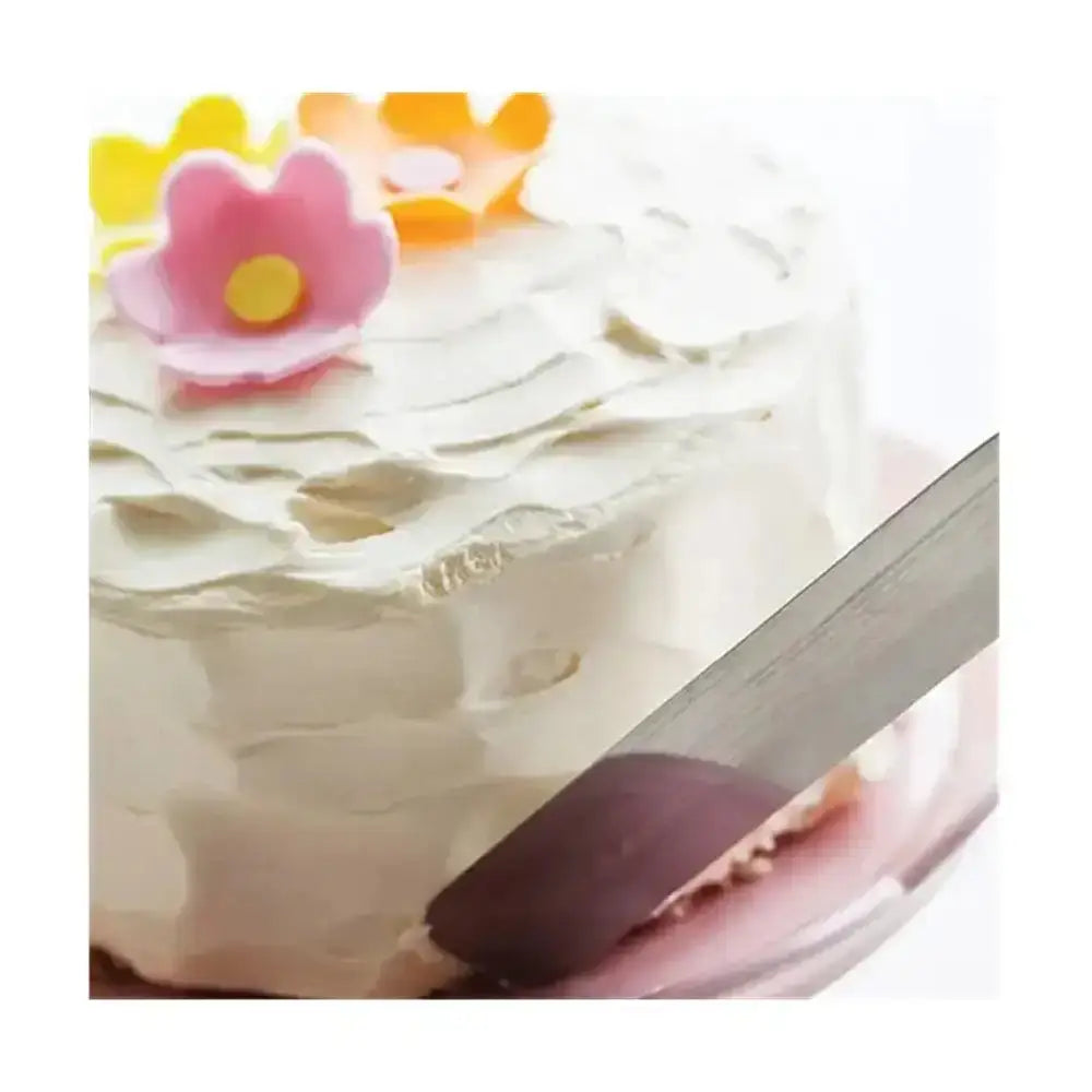 White cake with floral decorations and a knife cutting into it on a white background