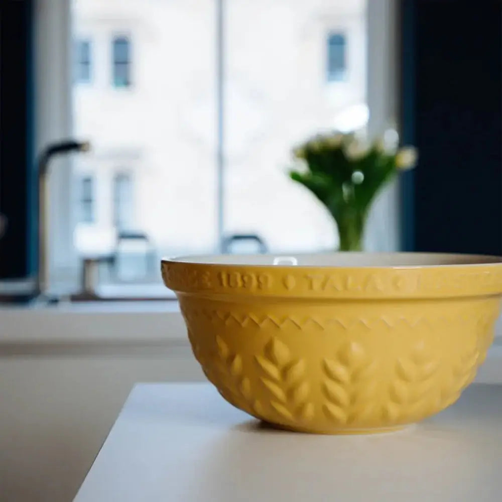 Yellow mixing bowl on a kitchen counter with a blurred background