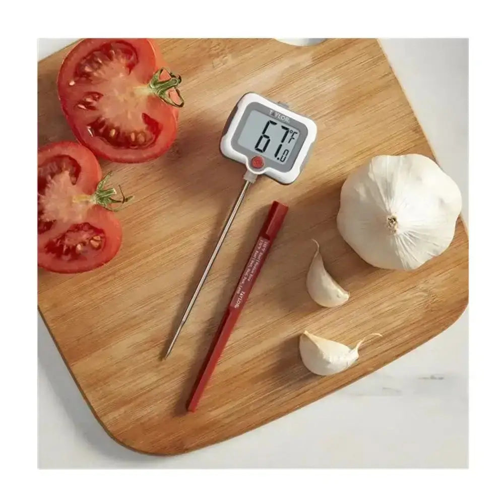 Digital thermometer on a wooden cutting board with tomatoes and garlic
