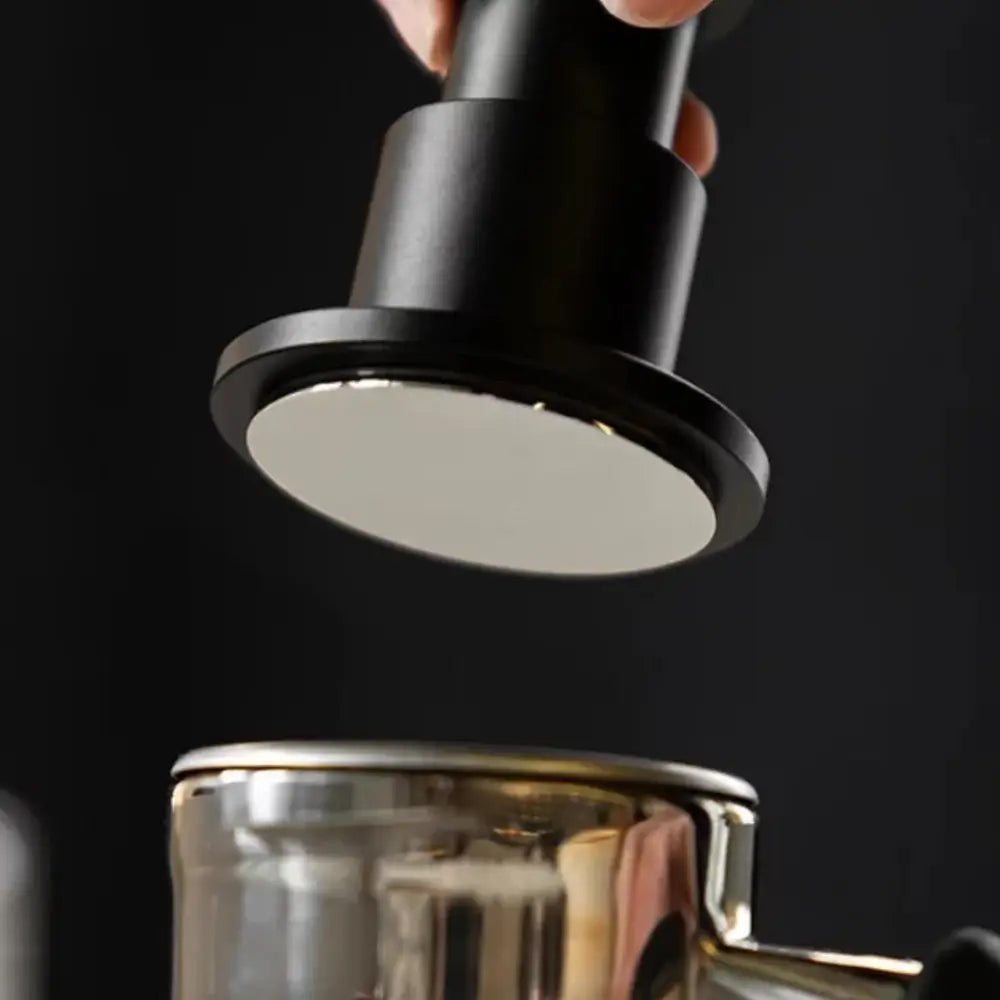Black coffee filter being placed into a silver coffee press against a black background