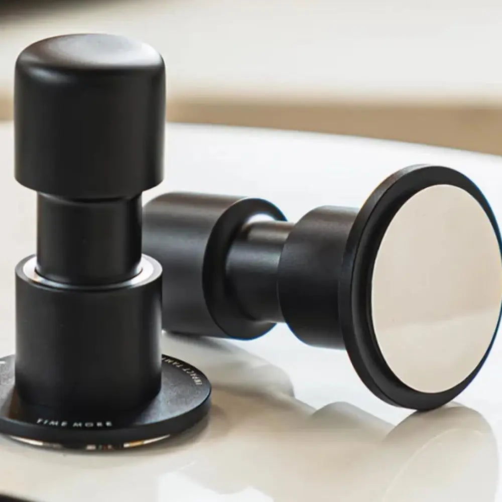 Black coffee tamp with a white interior on a reflective surface