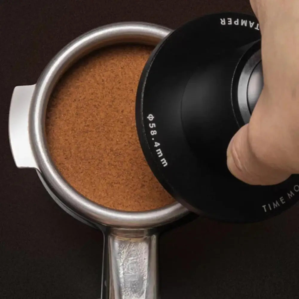 Coffee tamping process with a tamper and coffee grounds in a portafilter.
