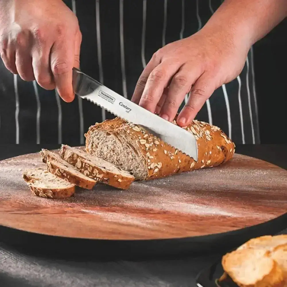 Person slicing bread with a serrated knife on a wooden board