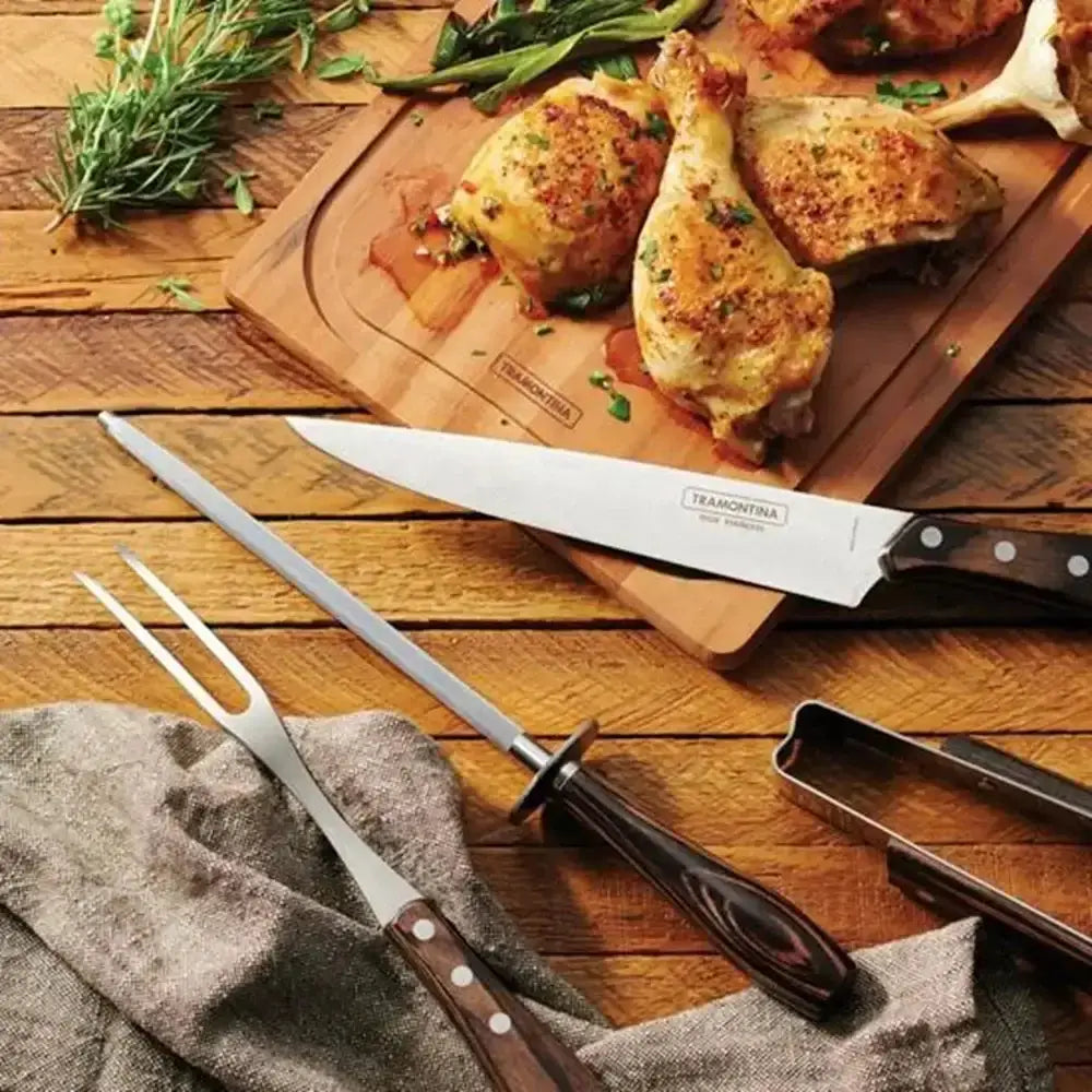 Roasted chicken pieces on a wooden cutting board with Tramontina kitchen tools.