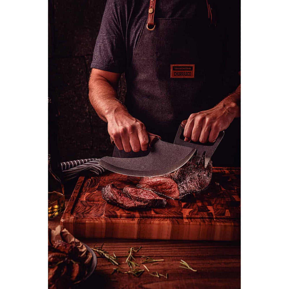 Person holding a cleaver over a wooden cutting board with meat on a dark background