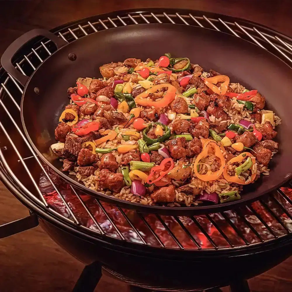 Fried rice with vegetables and meat in a wok on a grill