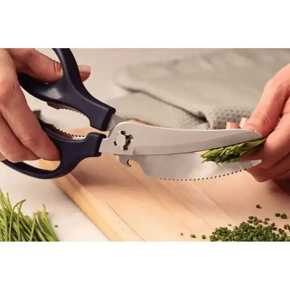 Person using kitchen shears to trim green herbs on a wooden cutting board.