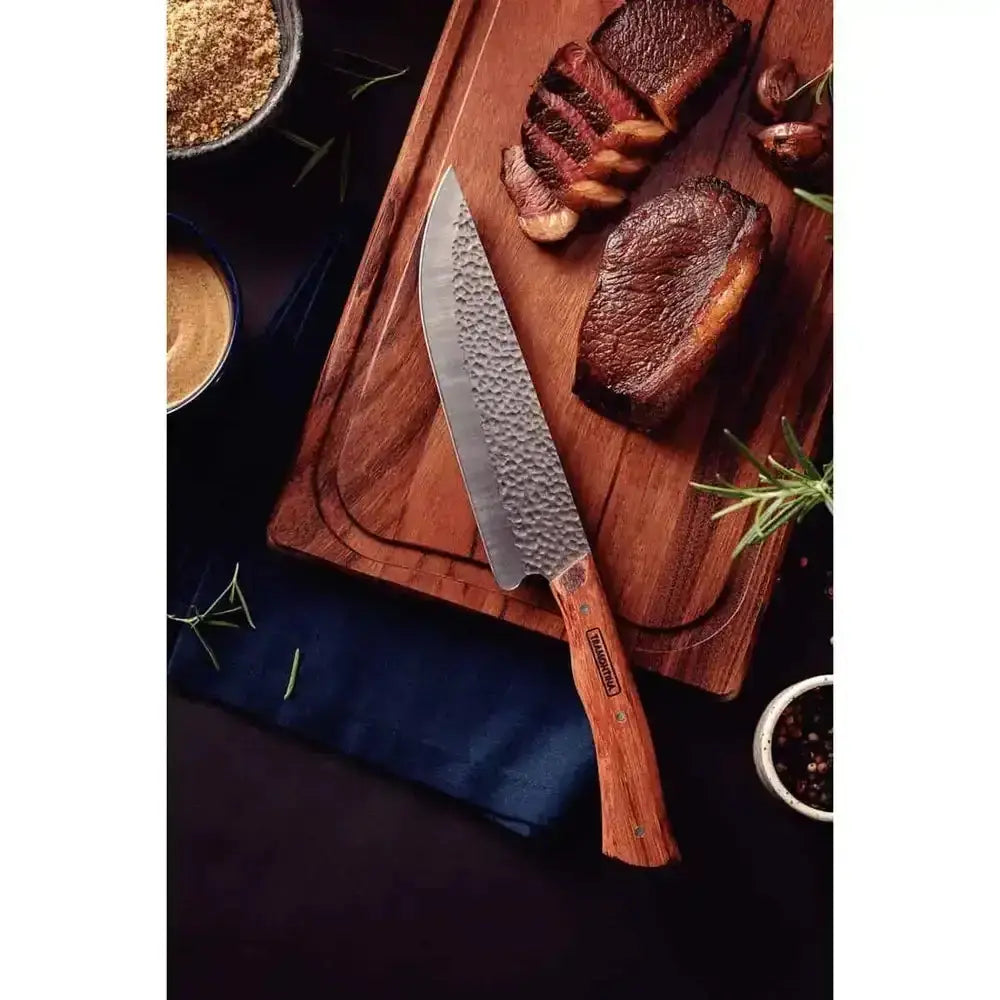 Chef's knife with wooden handle on a cutting board with grilled meat and spices