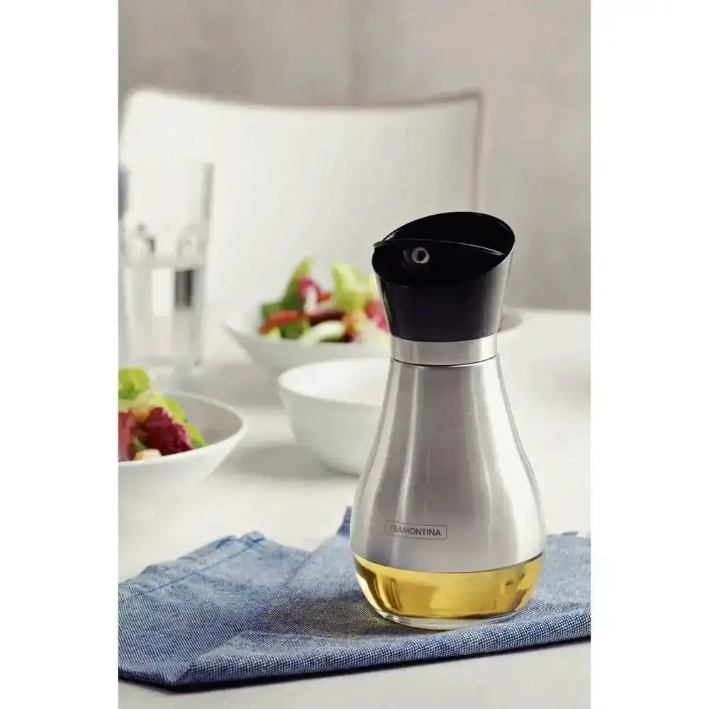 Silver and black oil dispenser on a blue napkin with a blurred background of a kitchen setting.