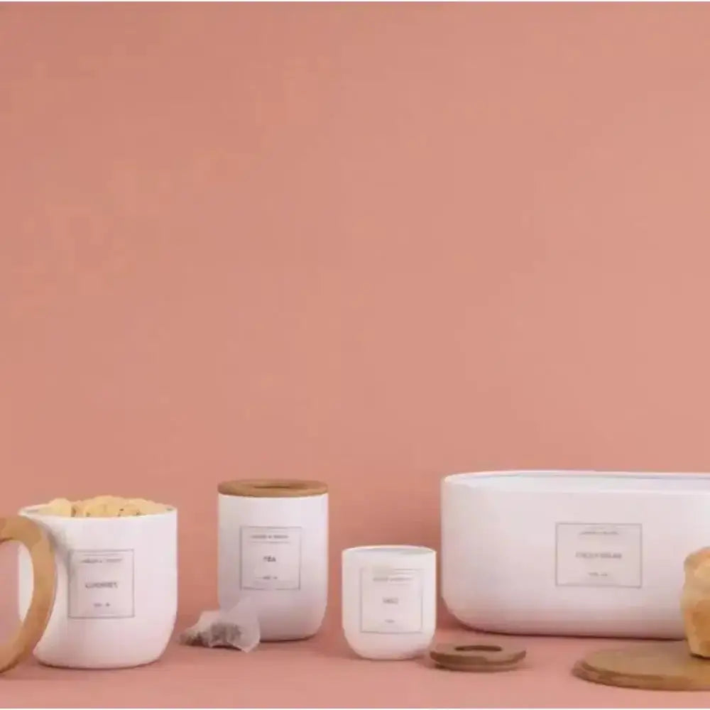 White ceramic typhoon eden storage canisters with reusable labels and natural wood lids in a modern kitchen setting