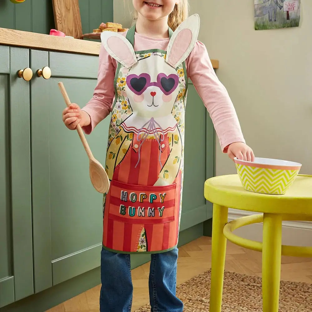 Child wearing a 'Happy Bunny' apron in a kitchen setting