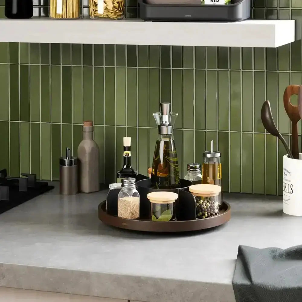 Kitchen counter with a tray holding various bottles and containers against a green tiled wall.