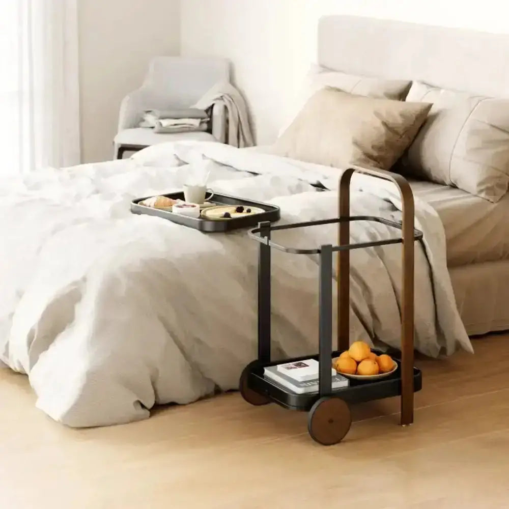 Black serving cart with a tray on a bed in a bedroom setting