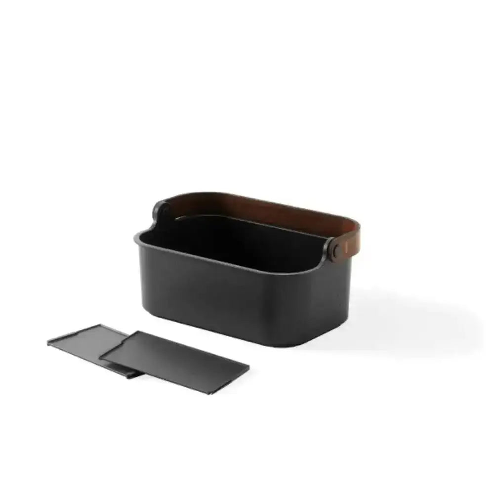 Black metal basket with a brown leather handle on a white background