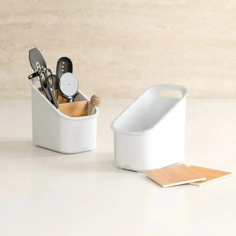 White cutlery organizer with utensils on a light surface.