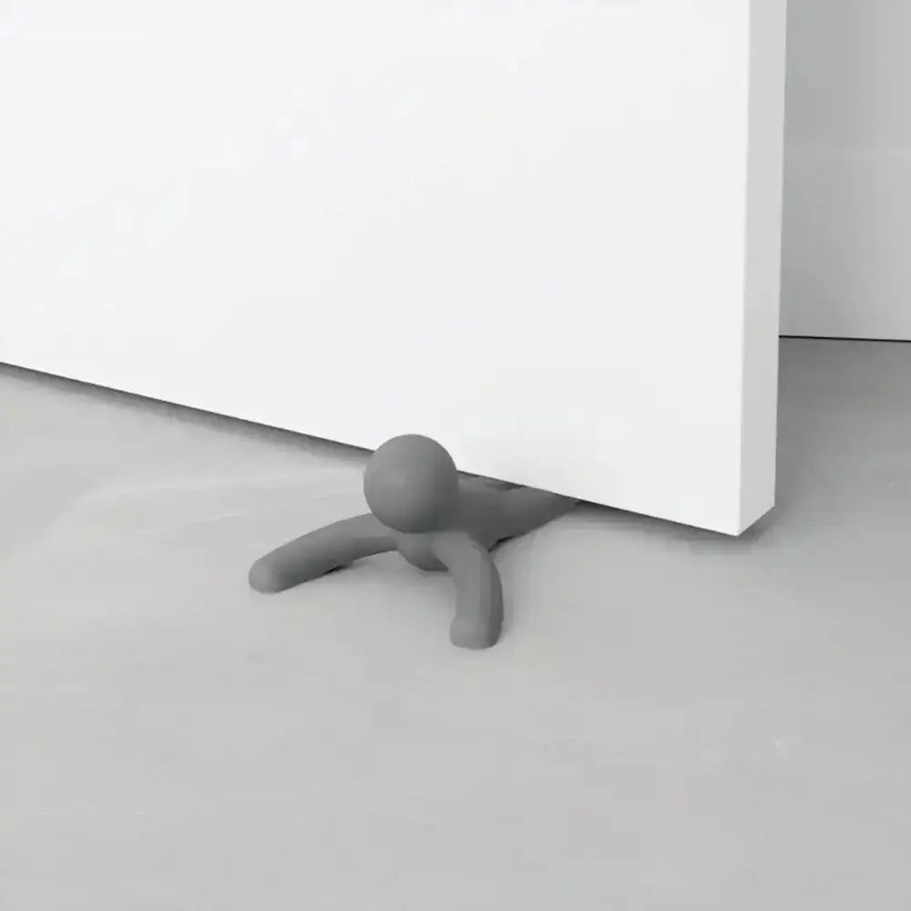 Gray door stopper attached to a white door on a light gray floor.