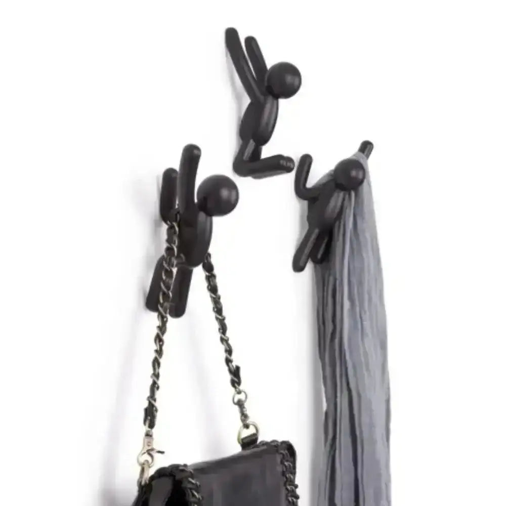 Black wall hooks holding a handbag and a scarf on a white background