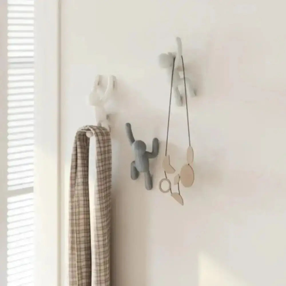 Gray wall hooks with decorative items on a light-colored wall.