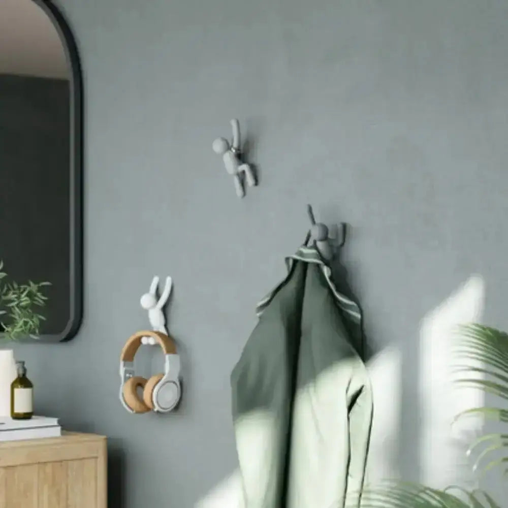 Decorative wall hooks on a gray wall with a green towel and headphones.