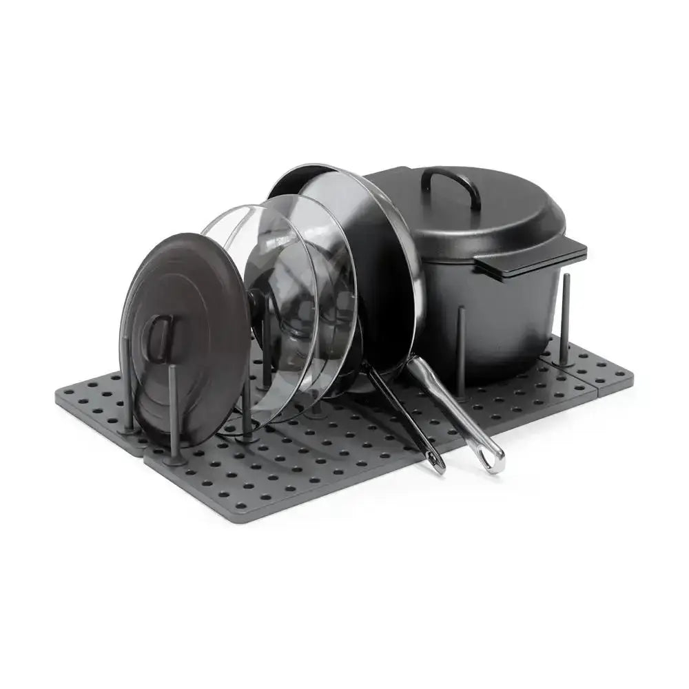 Set of black cookware with lids on a metal stand against a white background